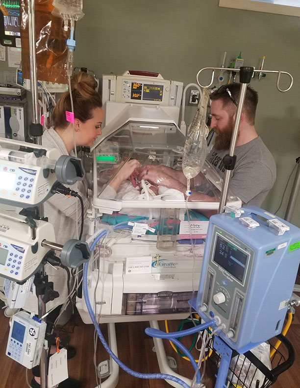 mom and dad with baby in nicu