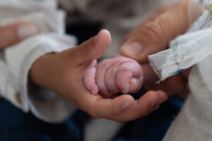 Child holding hands with newborn sibling