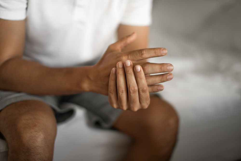 Man suffering from hand joint pain injury at home