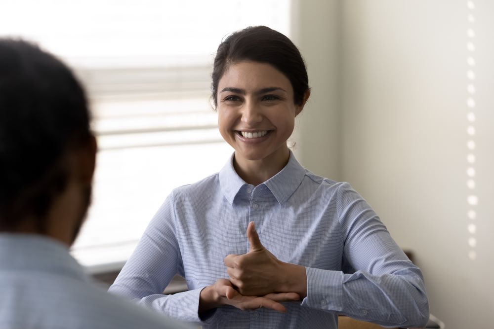 Smiling young woman using sign language, communicating with doctor