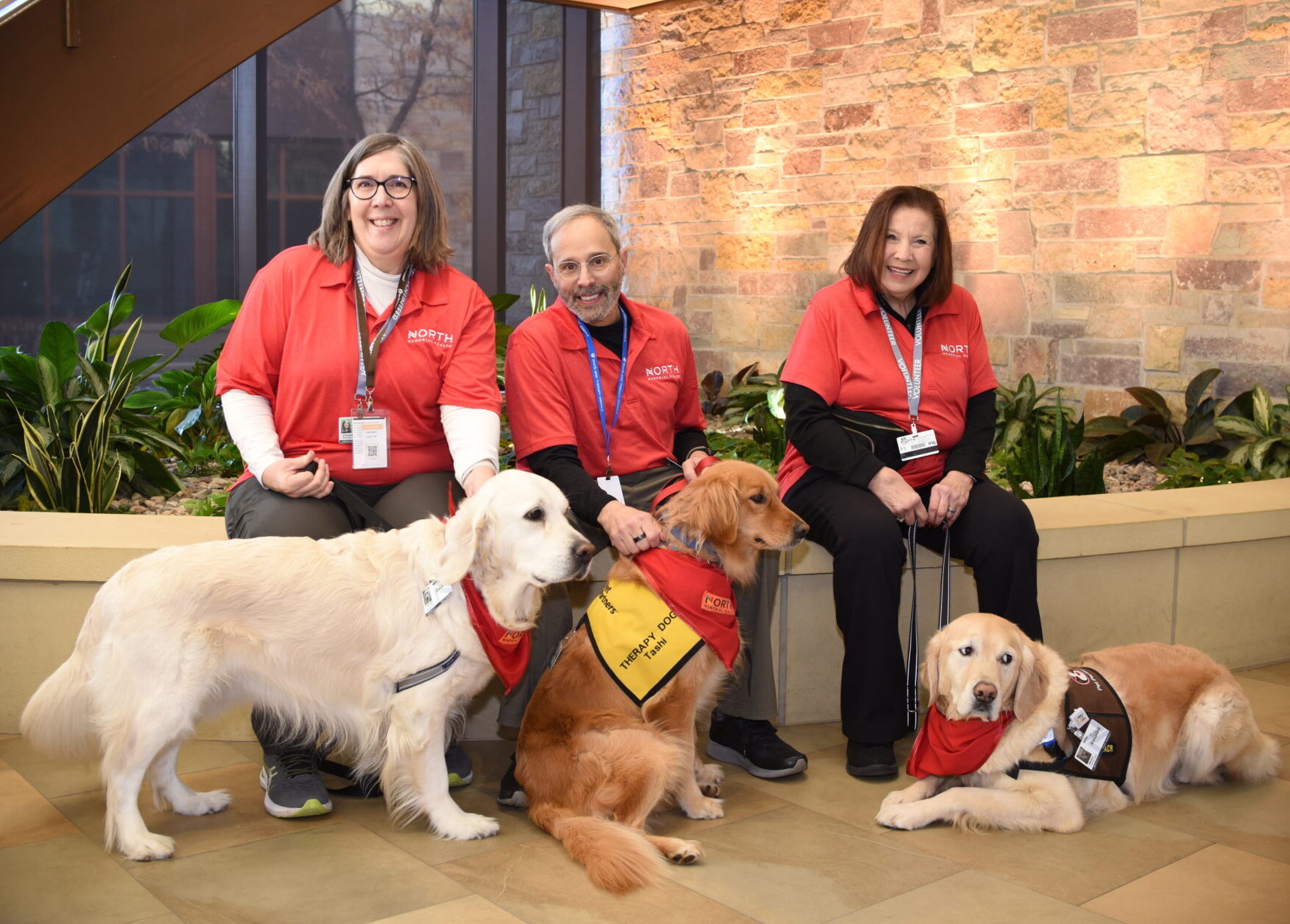 Three volunteers at Maple Grove Hospital with three therapy dogs