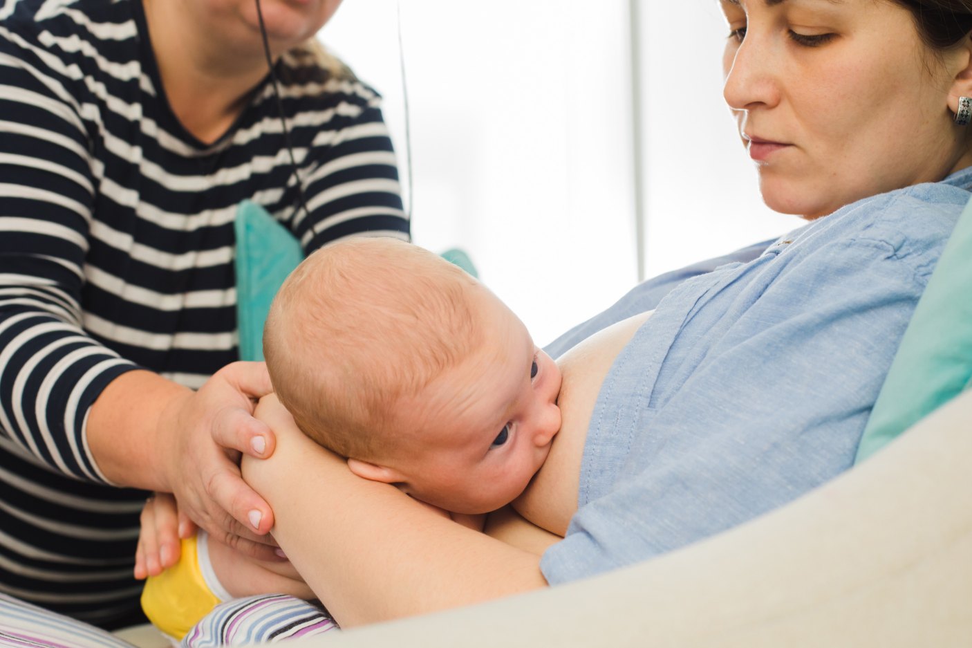 Mother breastfeeding baby with the support of a lactation consultation
